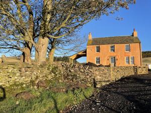 una casa de naranja con una pared de piedra y árboles en Townhead, en Peebles