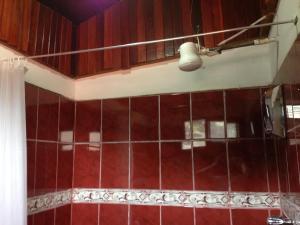baño con paredes de azulejos rojos y una luz en EL-CACIQUE-guesthouse-since-2003 en Santiago Este