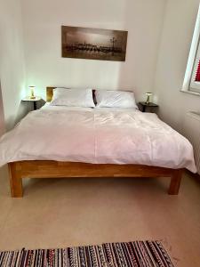 1 dormitorio con 1 cama grande con sábanas y almohadas blancas en Gäste-Appartement-Kirsammer, en Eningen unter Achalm