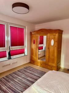 ein Schlafzimmer mit einem Holzschrank und zwei Fenstern in der Unterkunft Gäste-Appartement-Kirsammer in Eningen unter Achalm