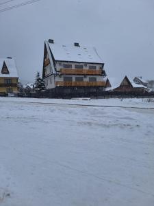 a large building with snow on top of it at Apartament Wiktoria in Kluszkowce