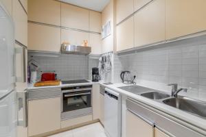 Appartement aan Zee Oostende في أوستند: مطبخ مع دواليب بيضاء ومغسلة