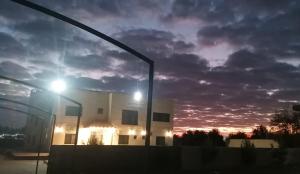 a building with a street light and a cloudy sky at Caprios motel in Al Qasţal