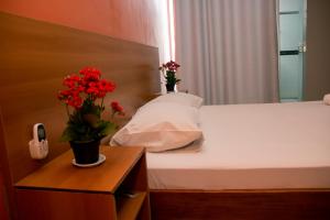 Un dormitorio con una cama con dos flores. en Motel Malibu en Divinópolis