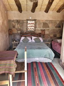 1 dormitorio con 1 cama en una pared de piedra en El Cerrito en Maimará