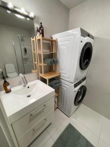 a bathroom with a washing machine next to a sink at Ny lägenhet på markplan med havsutsikt in Strömstad