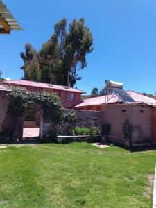 a yard with two buildings and a grass field at Taquile Familia Celso in Huillanopampa