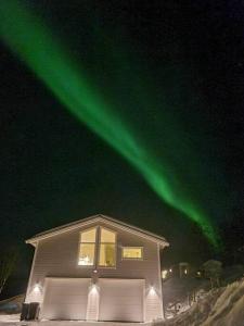 a house with the green northern lights in the sky at All new, fully equipped apartment at the gate of Senja 