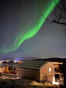 an aurora in the sky over a house at All new, fully equipped apartment at the gate of Senja 