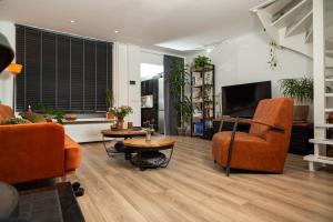een woonkamer met oranje stoelen en een tv bij Sfeervol verblijf nabij centrum Almelo in Almelo