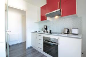 a kitchen with white counters and red cabinets at Mont Royal balcon et piscine in Annecy