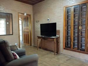 een woonkamer met een flatscreen-tv aan de muur bij Casa completa em meio à natureza in Passa Quatro