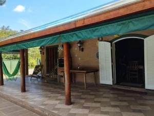 een patio met een groene luifel en een tafel bij Casa completa em meio à natureza in Passa Quatro