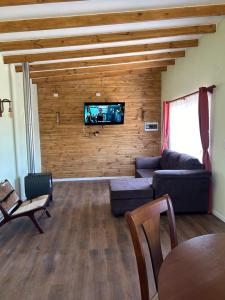 uma sala de estar com um sofá e uma televisão na parede em Cabañas Vista Volcanes II em Puerto Varas