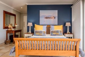 a bedroom with a bed with yellow and blue walls at Zeezicht Apartments in Stompneusbaai