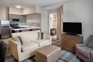 Fairfield Inn & Suites by Marriott Airdrie في إيرداري: غرفة معيشة مع أريكة وتلفزيون بشاشة مسطحة