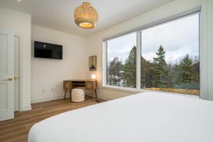 1 dormitorio con ventana grande, cama y escritorio en The White Rose Chalet, en Blue Mountains