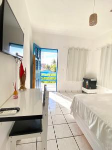 een slaapkamer met een bed en een bureau met een televisie bij Pousada Capitolio 01 - Canoa Quebrada - hospedagem in Canoa Quebrada