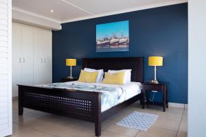 1 dormitorio con paredes azules y 1 cama con almohadas amarillas en Zeezicht Apartments, en Stompneusbaai