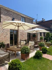 un patio con 2 mesas y 2 sombrillas en Les Hortensias, en Canly