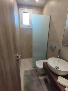 ein Bad mit einem Waschbecken, einem WC und einem Fenster in der Unterkunft PortoHeli Matilda`s house 2 in Porto Heli