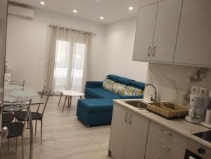 uma cozinha e uma sala de estar com um sofá azul em PortoHeli Matilda`s house 2 em Porto Heli