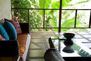 een woonkamer met een glazen tafel en stoelen bij Samai Lodge Holistic Living in Olón