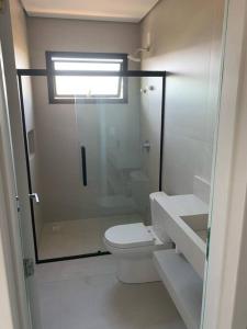 a bathroom with a toilet and a glass shower at Apto inteiro 2 quartos, condomínio com piscina aquecida in Bombinhas