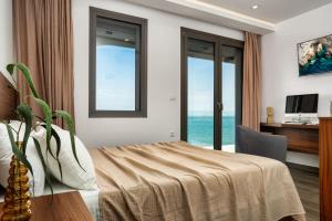 a bedroom with a bed and a desk and windows at Violet Beach Front Private Villa in Laganas