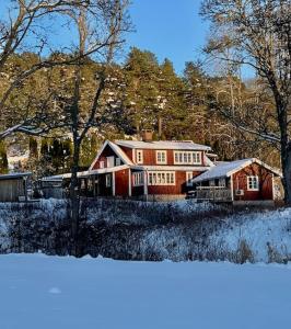Casa de madera grande con nieve en el suelo en Cozy cottage with sea view, en Svenshögen
