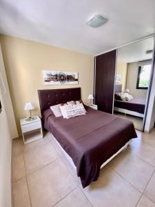 Un dormitorio con una cama grande y un espejo. en Dpto Edificio Tempo, en Villa Carlos Paz