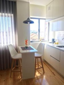 a kitchen with white cabinets and a table and chairs at Studio Jardim São Lázaro in Porto