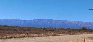 a dirt road with a fence and mountains in the background at Cabaña Dina in Santa Rosa del Conlara