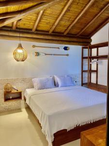 a bedroom with a white bed with a wooden ceiling at Chalé Del Mar in Morro de São Paulo