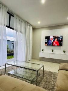 a living room with a glass table and a tv at Ekhaya Luxury Apartment in Lobamba