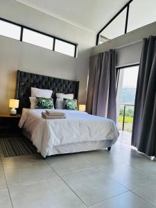 a bedroom with a large bed with a large window at Ekhaya Luxury Apartment in Lobamba