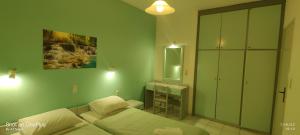 a green room with two beds and a mirror at MENTA APT in Agia Pelagia
