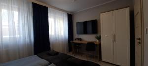 a bedroom with a bed and a desk and a television at Solanki Central Apart in Inowrocław