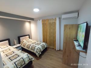 1 dormitorio con 2 camas y TV de pantalla plana en Olympic Tirana en Tirana