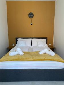 1 cama con almohadas blancas y reloj en la pared en Shubu GARDEN Vendégházak, en Szilvásvárad