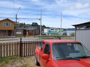 un camión rojo estacionado junto a una valla de madera en Hostal Sandrita en Castro