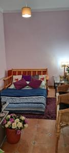 Un dormitorio con una cama con almohadas moradas y una mesa. en Casa Lavradores, Torrao en Torrão