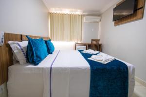 een slaapkamer met een groot bed met blauwe kussens bij Império Romano Thermas - BVTUR in Caldas Novas