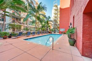 聖地牙哥的住宿－High-End San Diego Condo with Pool and Rooftop Access，一座游泳池,位于一座带椅子和棕榈树的建筑中