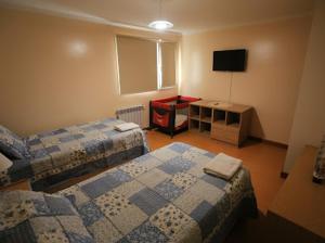 Una habitación de hotel con dos camas y un televisor. en Pinar suites, en San Carlos de Bariloche