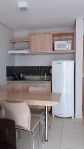 a kitchen with a wooden table and a white refrigerator at Apartamento 704-C Casa da Madeira Caldas Novas in Caldas Novas