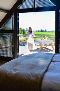 kobieta w białej sukience stojąca obok łóżka w obiekcie Bedje in de polder w mieście Montfoort