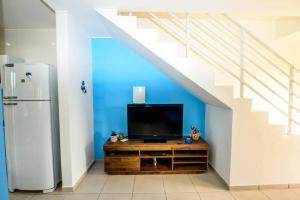 a tv sitting on a wooden dresser under a staircase at Casa de praia a 200 metros do mar in Florianópolis