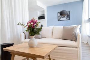 a living room with a white couch and a table with flowers at Lavanda Beautiful Apartment in Buenos Aires