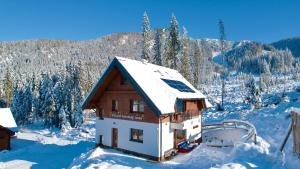 a house covered in snow with a mountain in the background at Villa pod hviezdami Jasná in Belá